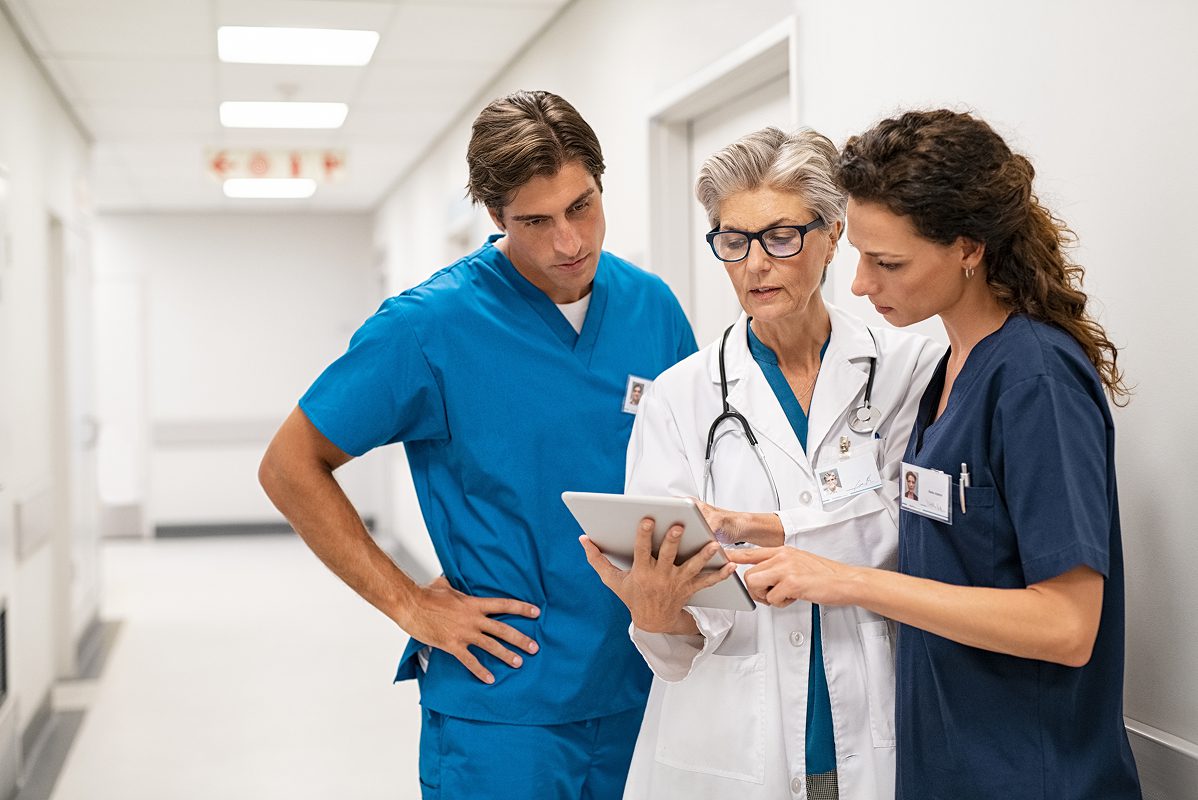 Three healthcare professionals looking at a tablet | Clinical Registry Solutions